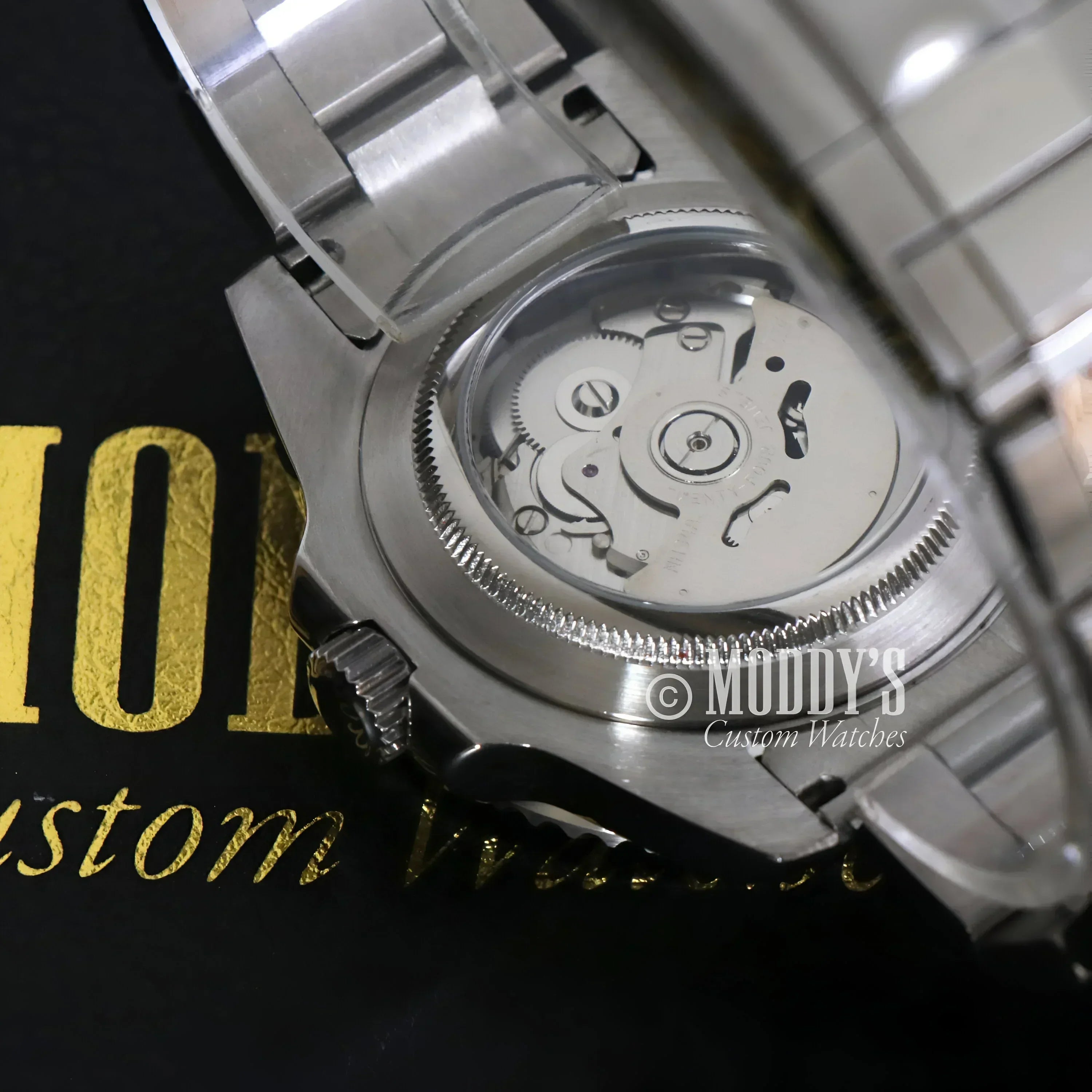 Silver wristwatch GMTeiko Batman with exposed NH34 automatic movement showcasing Seiko mod GMT