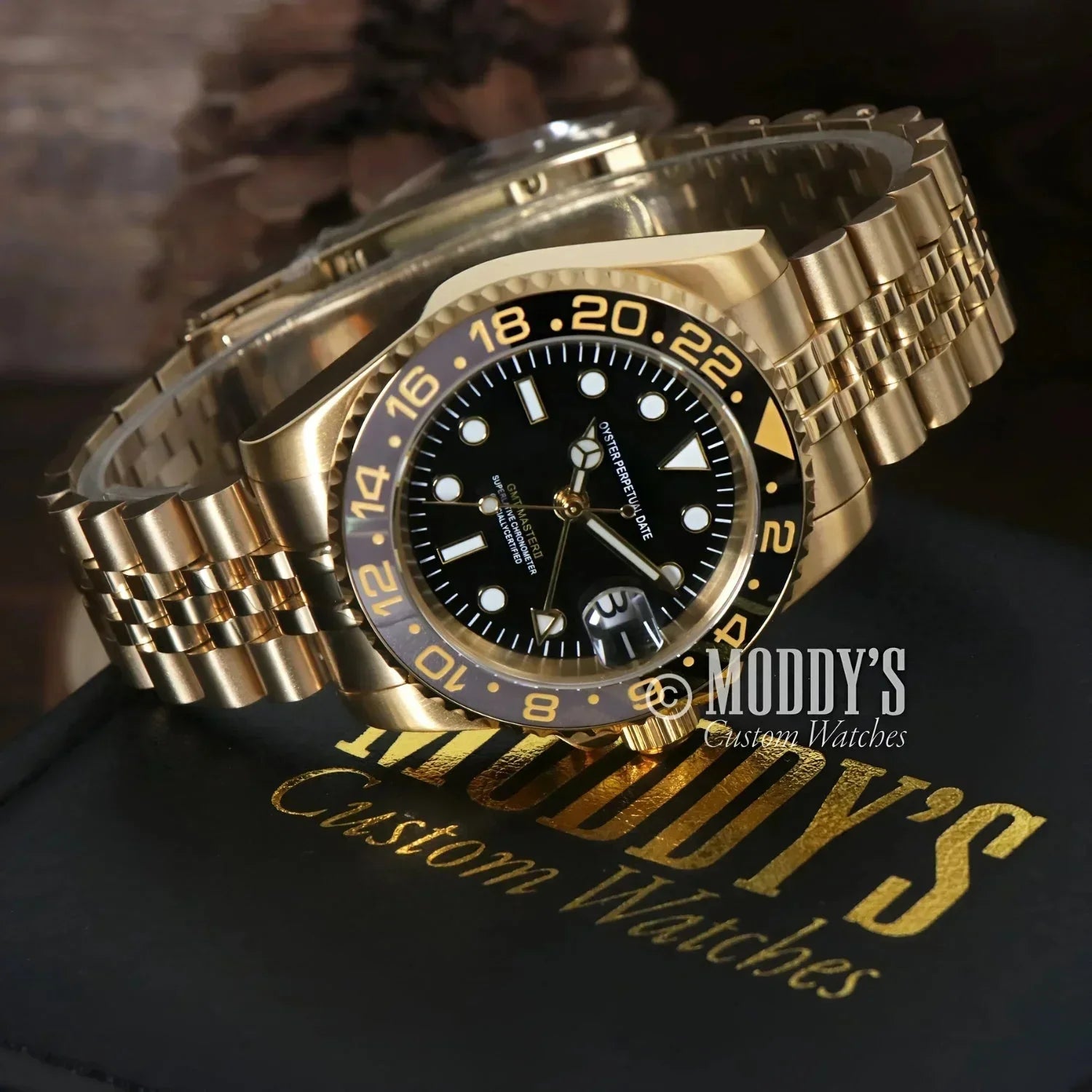 Gold wristwatch with black face featuring Seiko NH34 automatic movement in GMTeiko design