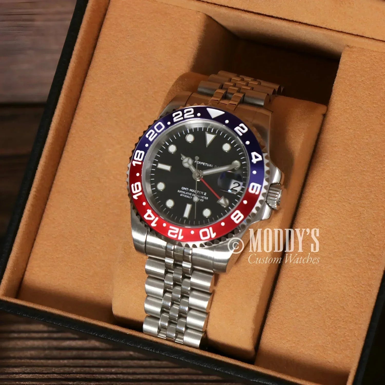Silver wristwatch with red and blue bezel, featuring Seiko NH34 automatic movement