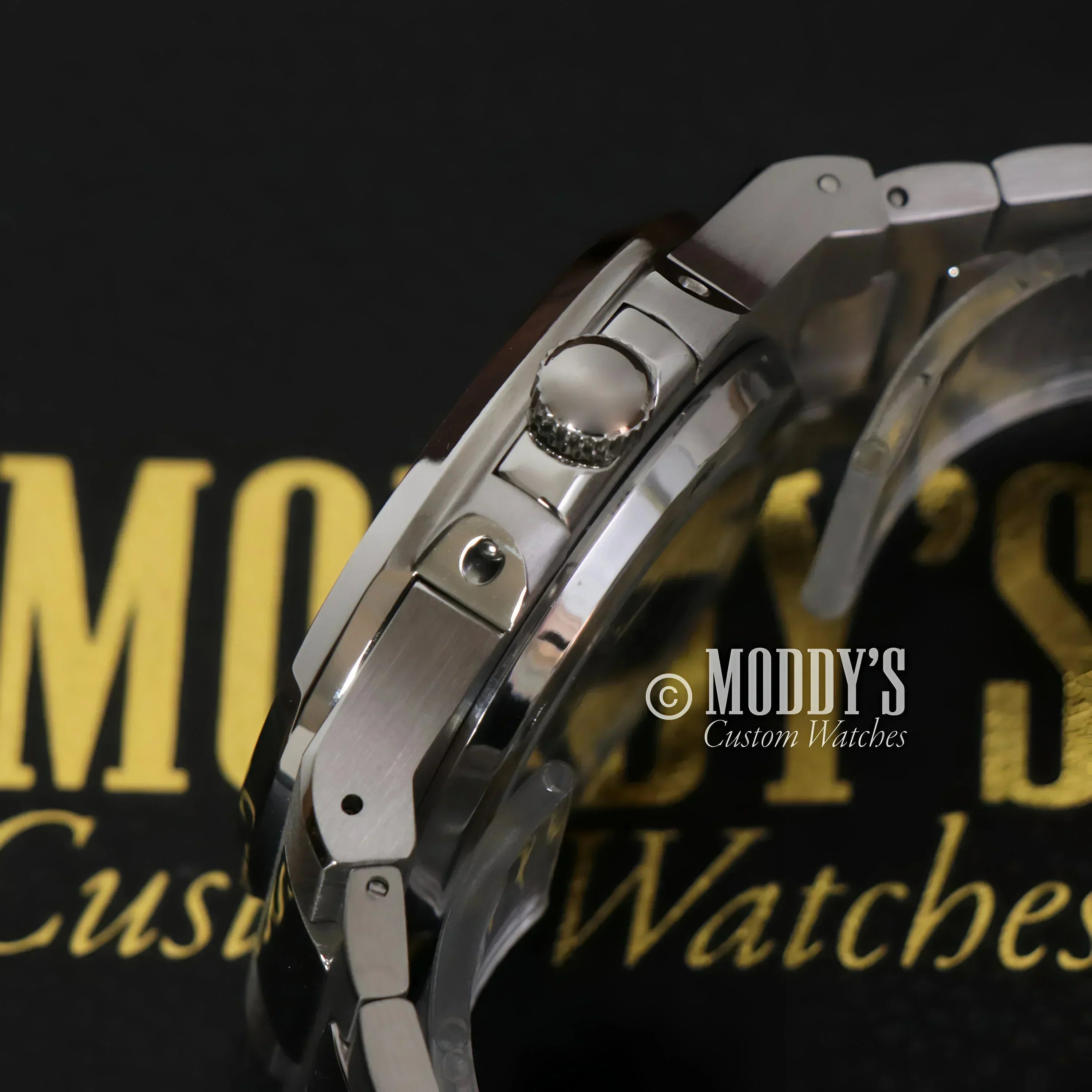 Silver wristwatch with textured crown from Nautiko featuring green open movement design