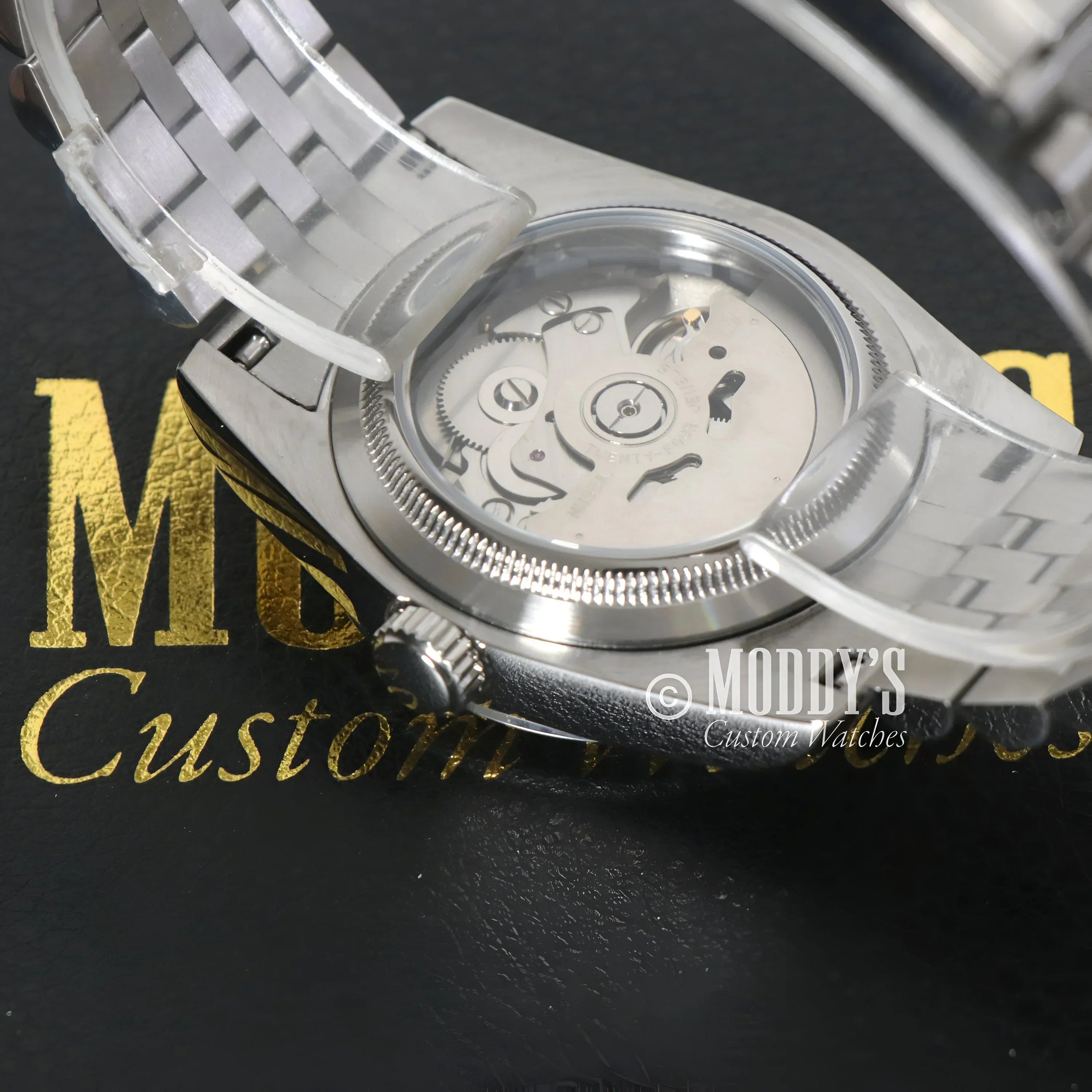 Silver wristwatch with exposed movement featuring NH35 automatic movement and 904L stainless steel