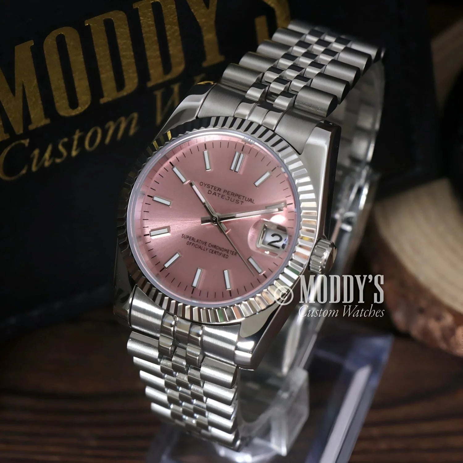 Silver wristwatch with pink face, featuring Seiko NH35 Automatic and 904L stainless steel