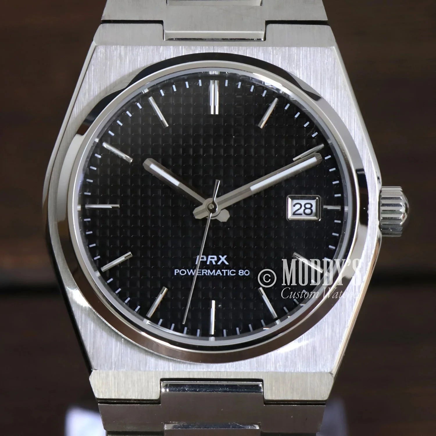 Silver wristwatch with black patterned face featuring Seiko NH35 automatic movement