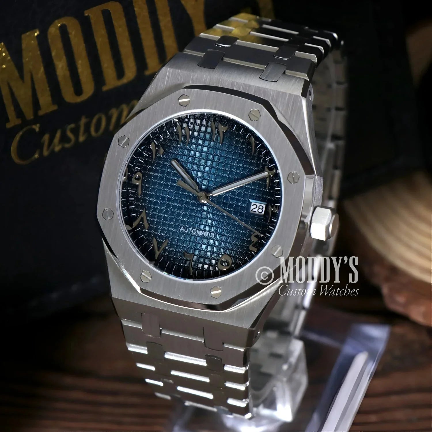 Silver wristwatch with blue patterned face, featuring Royal Seikoak and Arabic Blue design