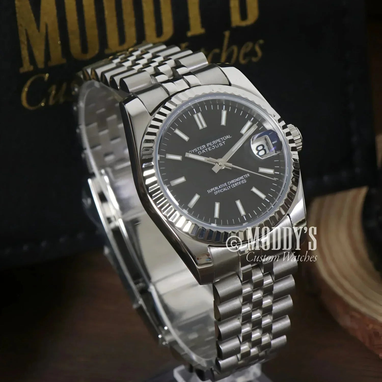 Silver wristwatch with black face from Seikojust, featuring Seiko NH35 automatic movement