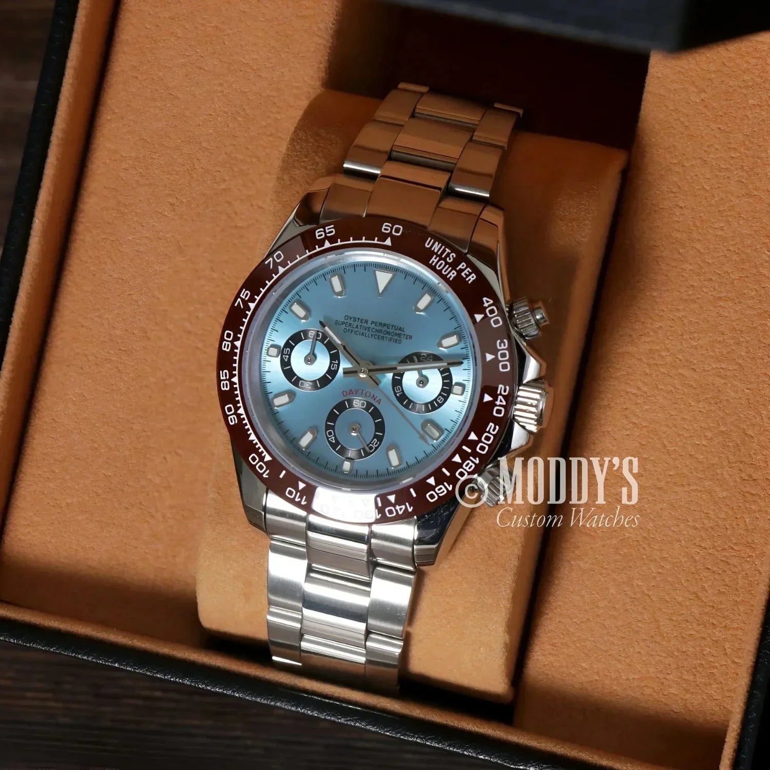 Silver wristwatch with light blue face and brown bezel, featuring Seiko VK63 hybrid movement