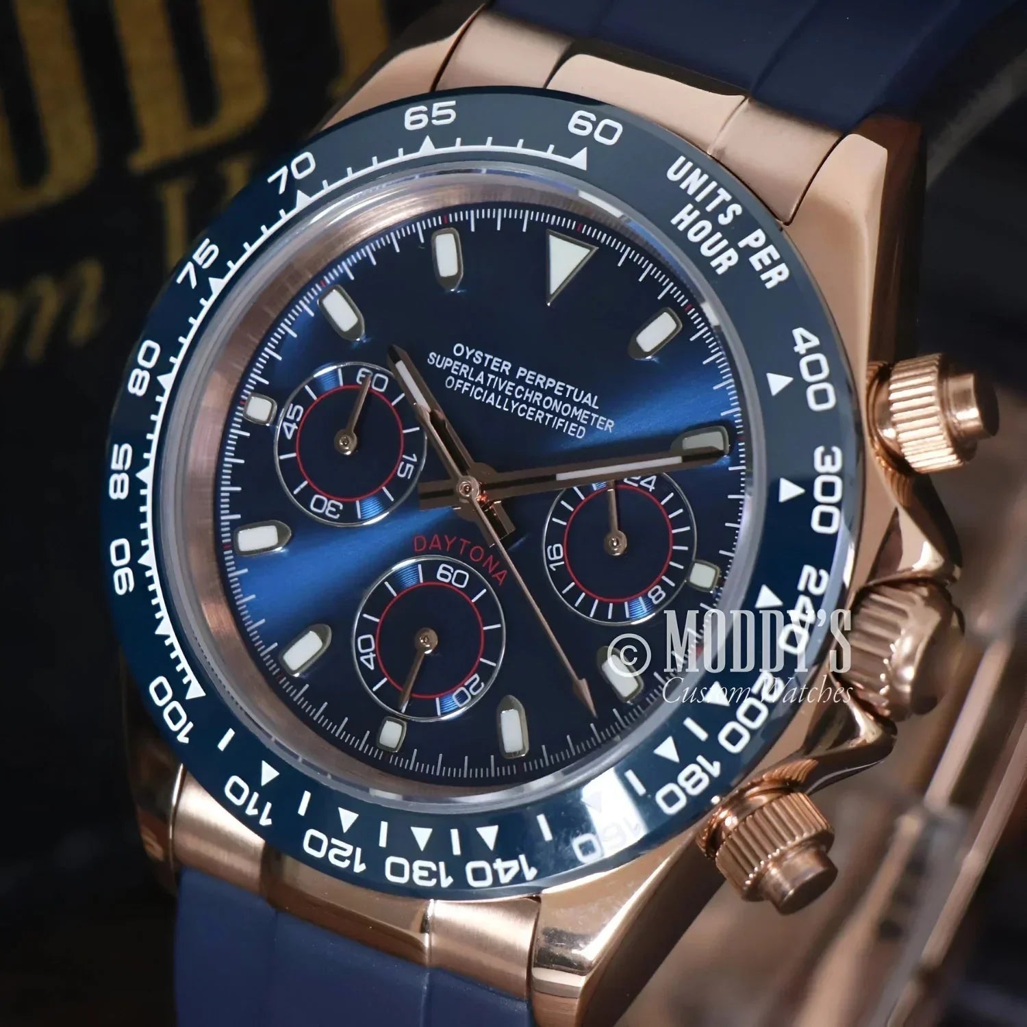 Rose gold Rolex Daytona watch with blue face and band, featuring Seiko VK63 hybrid movement