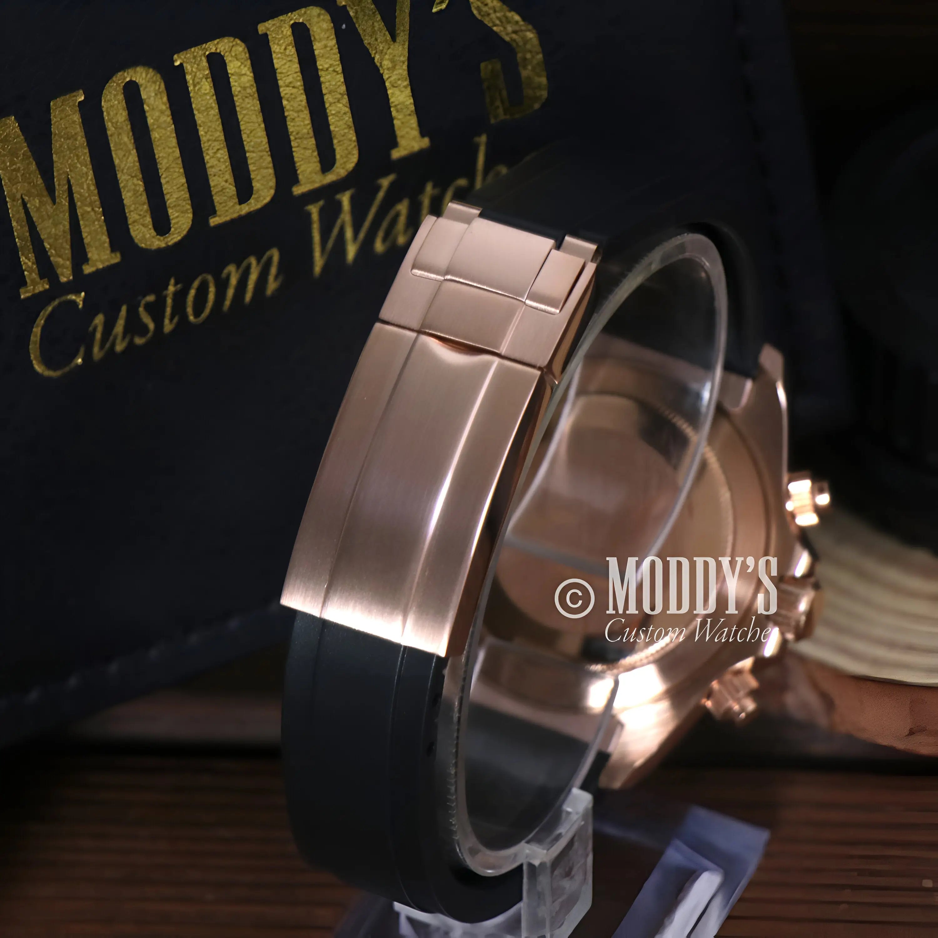 Seiko VK63 hybrid rose gold watch with black rubber strap on clear stand