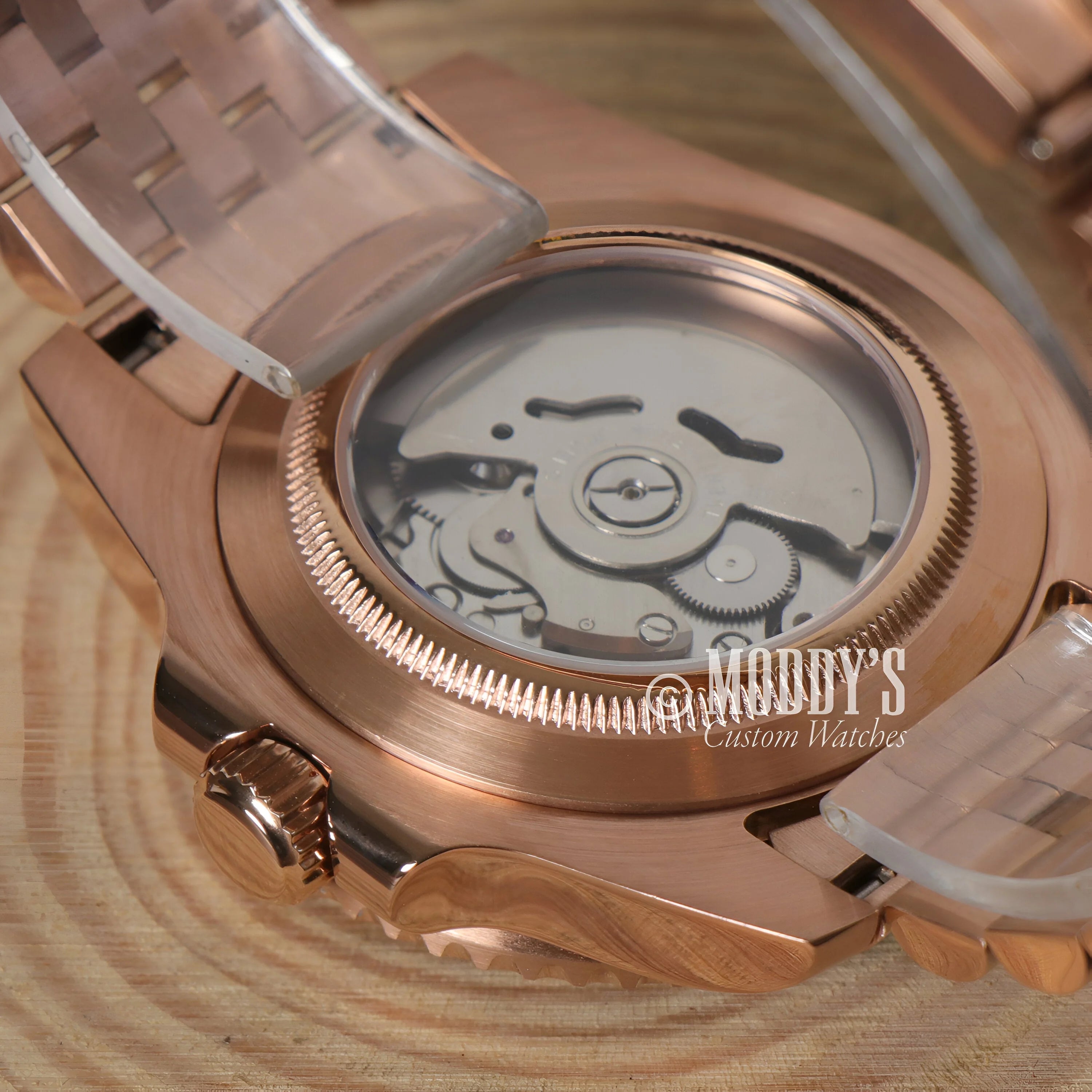 Rose gold GMTeiko watch with transparent case back showcasing GMT movement mechanism