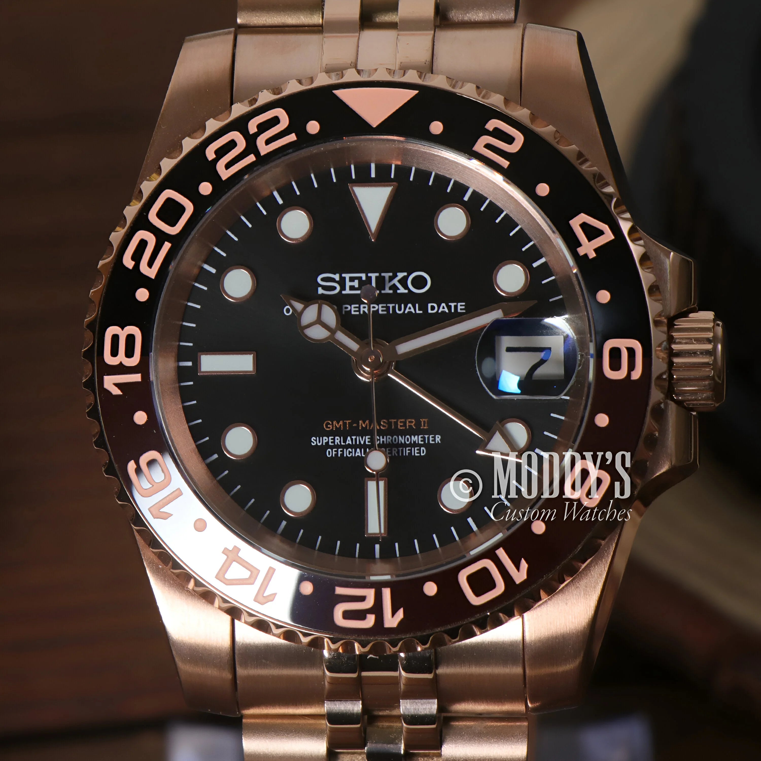 Seiko GMT dive watch with black dial and red/black bezel on a metal bracelet