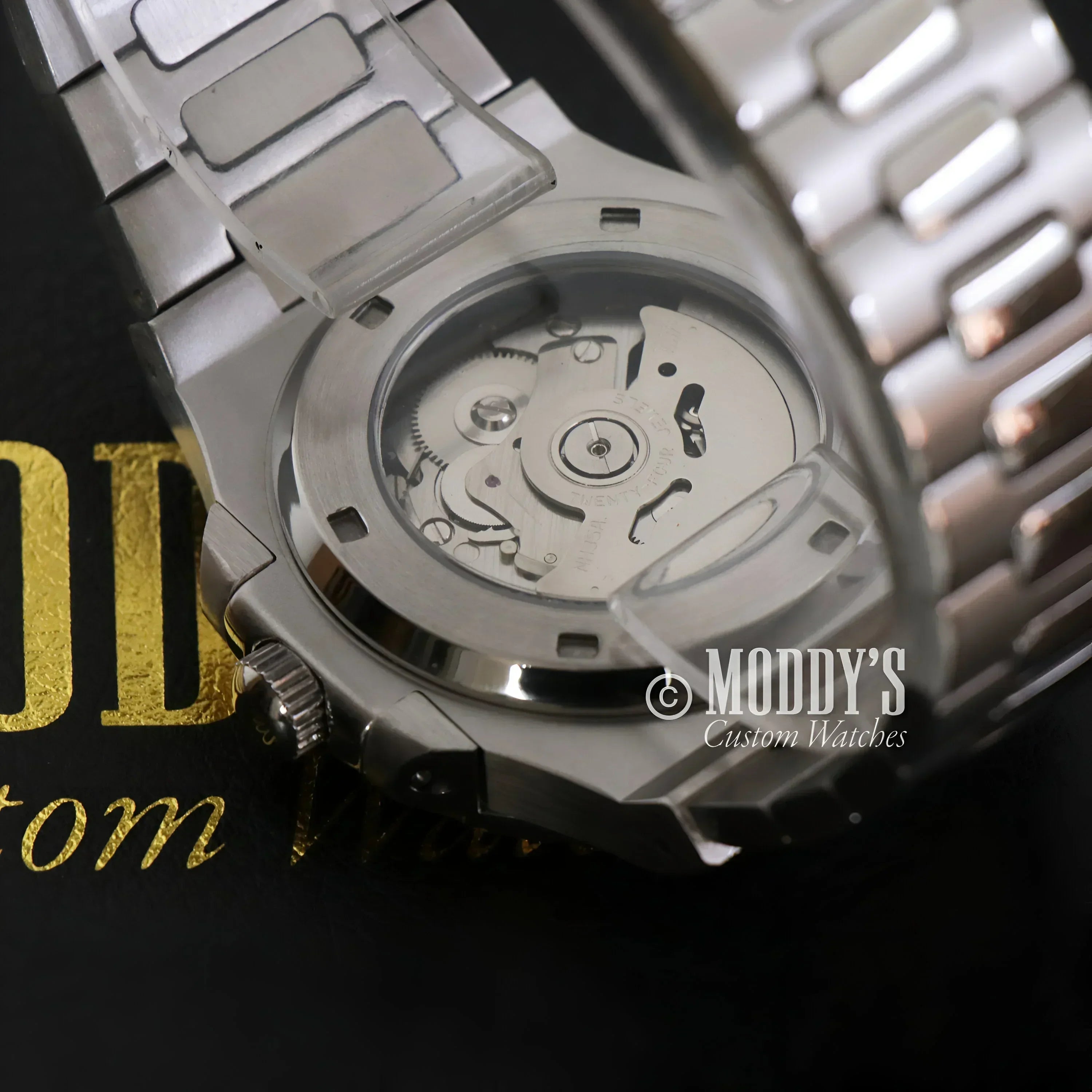 Silver wristwatch with olive green open movement featuring NH38 automatic movement