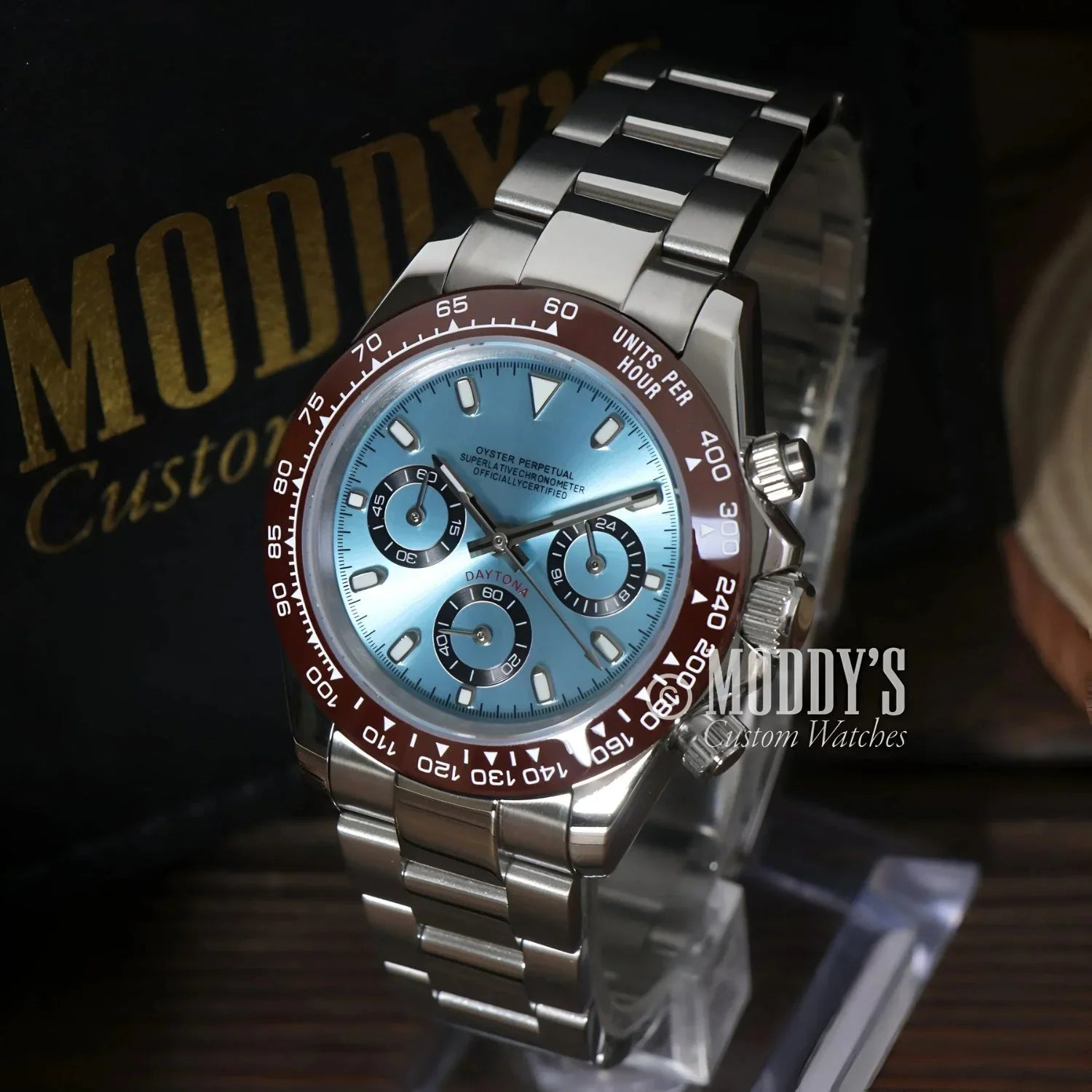 Silver wristwatch with light blue face and burgundy bezel featuring Seiko VK63 hybrid movement