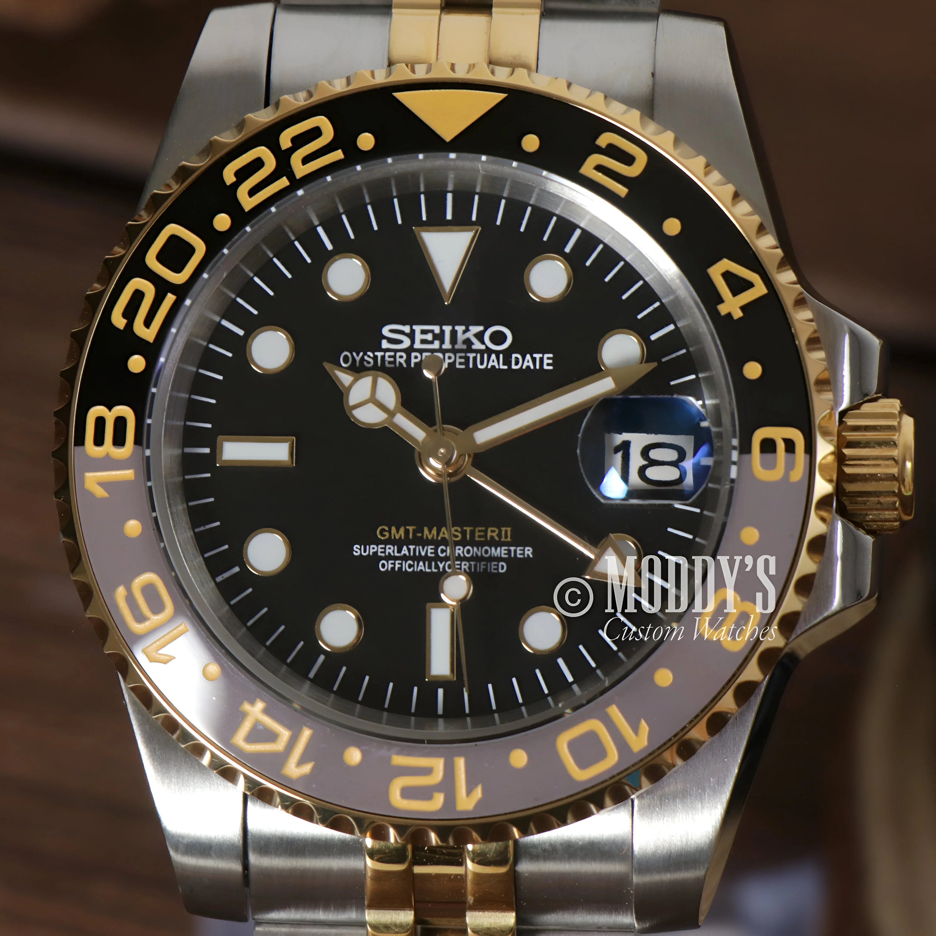 Seiko wristwatch with black dial, gold-tone bezel, and automatic movement in 904L stainless steel