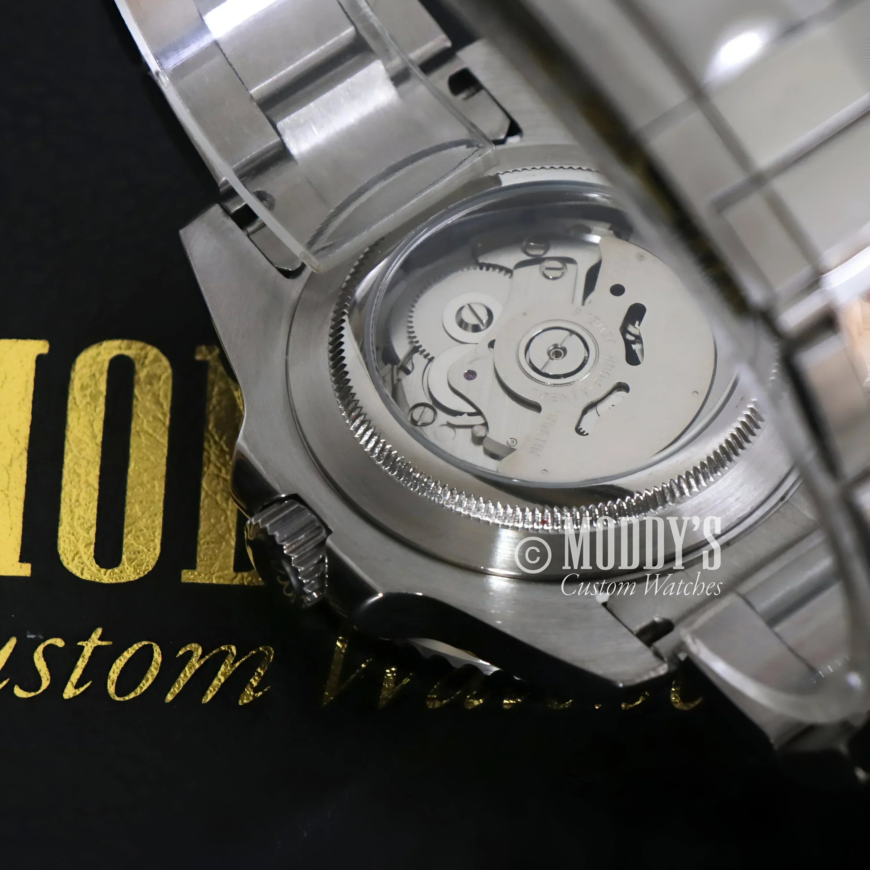 Silver wristwatch GMTeiko Batman with exposed NH34 automatic movement showcasing Seiko mod GMT