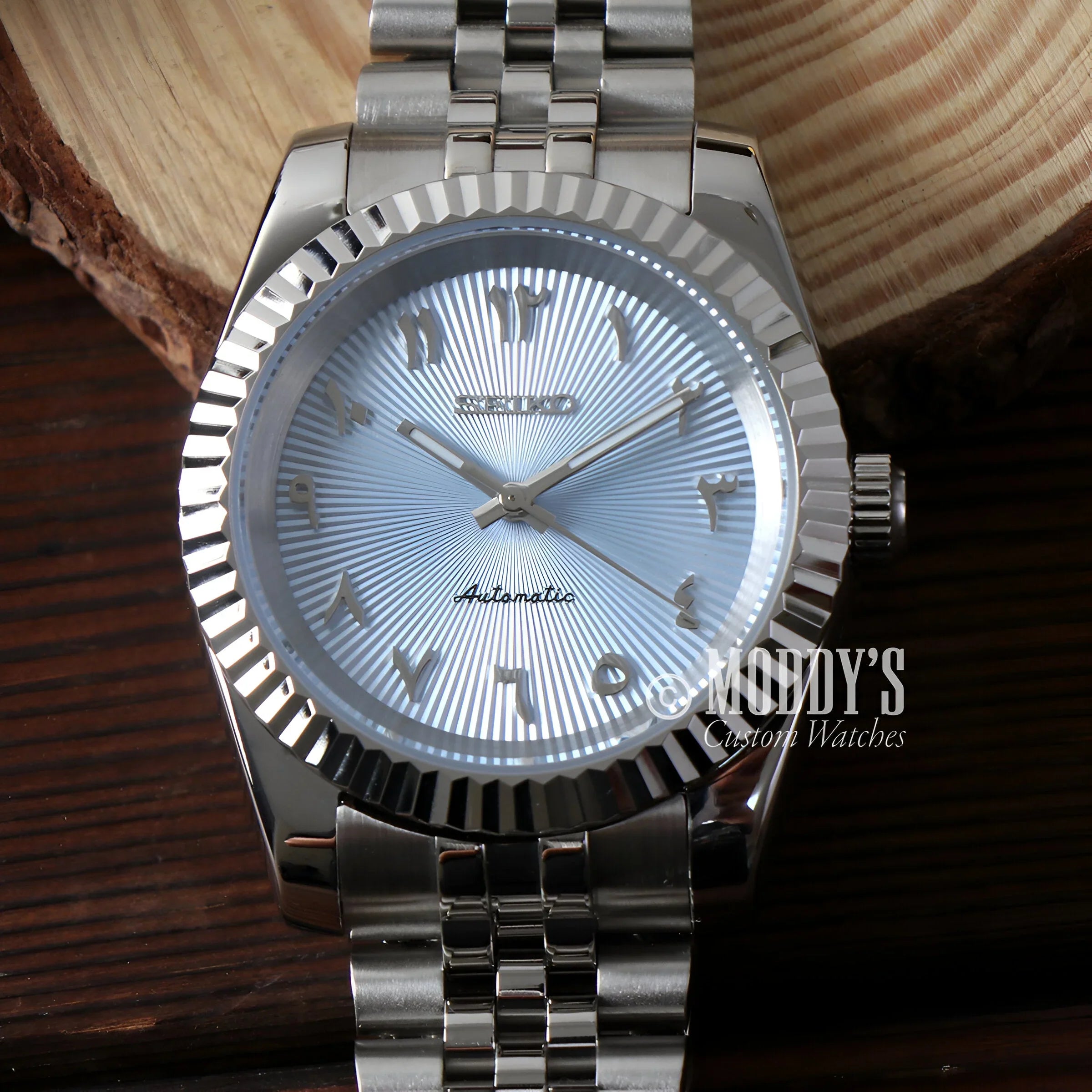 Seikojust Light Blue Arabic Textured Automatic Watch With a Silver Dial On a Wooden Table